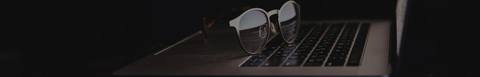 Pair of glasses resting on the keyboard of a laptop